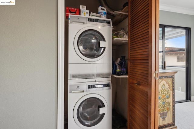 laundry room with carpet floors, stacked washer and clothes dryer, and crown molding