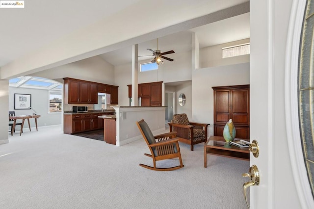 carpeted living room with ceiling fan and high vaulted ceiling