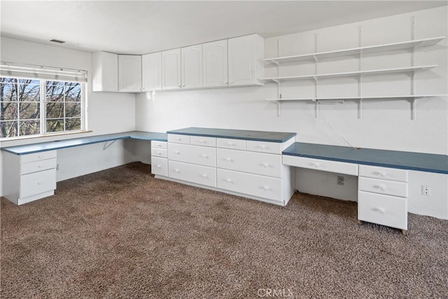 unfurnished office with built in desk and dark colored carpet