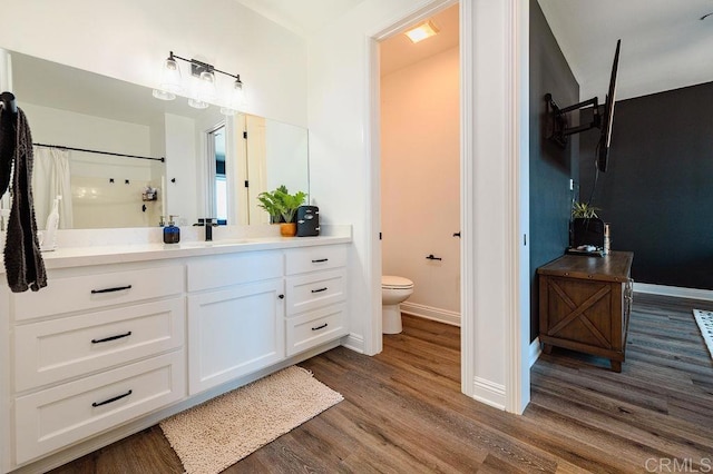 bathroom with toilet, hardwood / wood-style flooring, vanity, and curtained shower