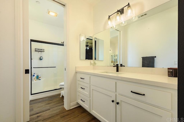 bathroom featuring walk in shower, vanity, toilet, and hardwood / wood-style flooring