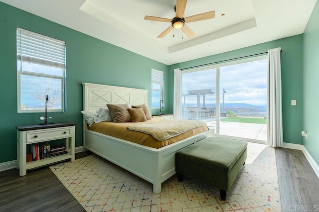 bedroom with a raised ceiling, access to outside, light hardwood / wood-style floors, and ceiling fan