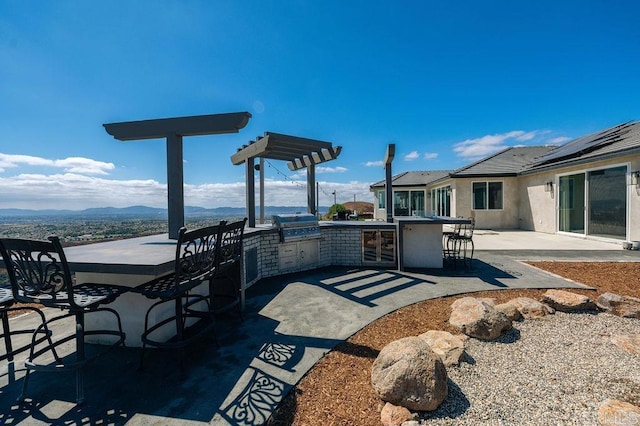 view of patio / terrace with a grill, exterior bar, a mountain view, and area for grilling