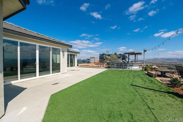 view of yard with an outdoor bar, a mountain view, and a patio