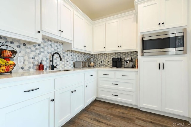 kitchen with white cabinets, stainless steel microwave, sink, and tasteful backsplash