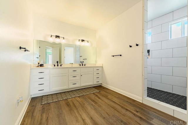 bathroom with hardwood / wood-style floors, vanity, and a tile shower