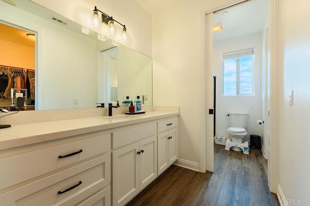 bathroom with toilet, hardwood / wood-style floors, and vanity