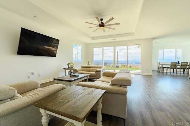 living room with ceiling fan, a tray ceiling, and hardwood / wood-style flooring