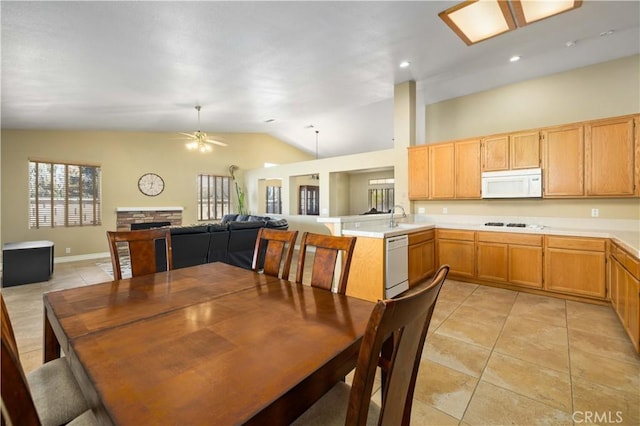 dining space featuring ceiling fan, light tile patterned flooring, a stone fireplace, and lofted ceiling