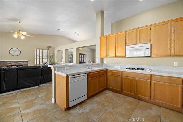 kitchen with lofted ceiling, ceiling fan, kitchen peninsula, sink, and white appliances