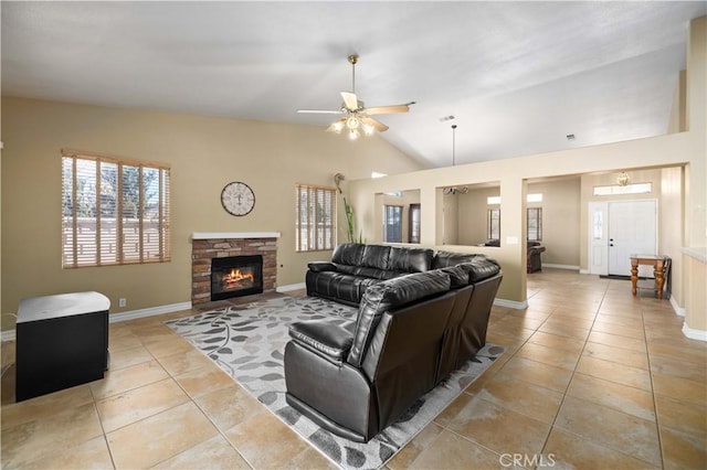 tiled living room with ceiling fan, a stone fireplace, and vaulted ceiling