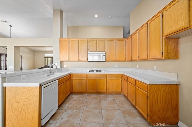 kitchen featuring kitchen peninsula, sink, white appliances, tile counters, and light tile patterned floors