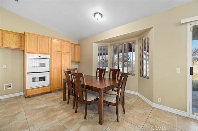 dining area featuring light tile patterned floors and vaulted ceiling