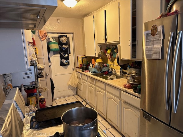 kitchen with sink, stainless steel fridge, tile counters, and light tile patterned flooring