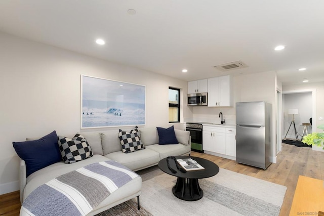 living room with light hardwood / wood-style floors and sink