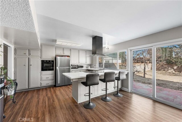 44028 Halcom Ave, Lancaster, CA 93536 - kitchen with kitchen peninsula, gray cabinets, island exhaust hood, a breakfast bar, and black appliances
