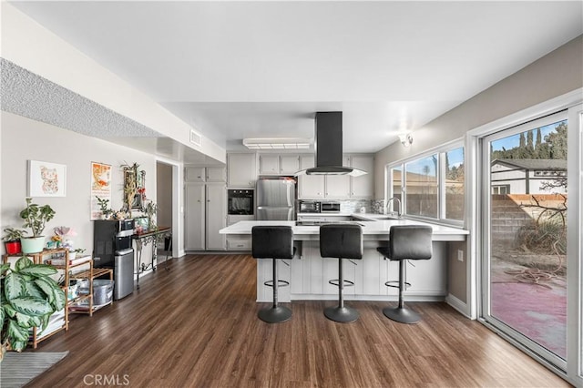 44028 Halcom Ave, Lancaster, CA 93536 - kitchen featuring oven, a breakfast bar, gray cabinetry, stainless steel fridge, and island range hood