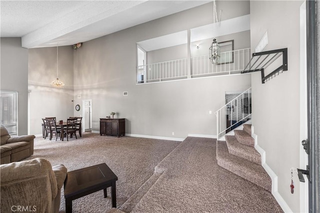 living room featuring carpet, a healthy amount of sunlight, a chandelier, and a high ceiling