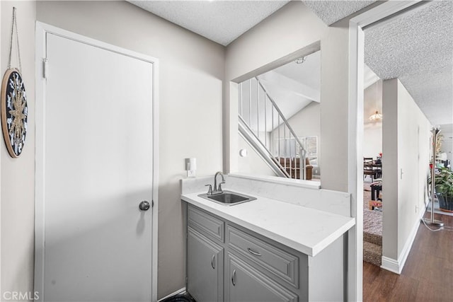 44028 Halcom Ave, Lancaster, CA 93536 - kitchen featuring a textured ceiling, dark wood-type flooring, gray cabinetry, and sink