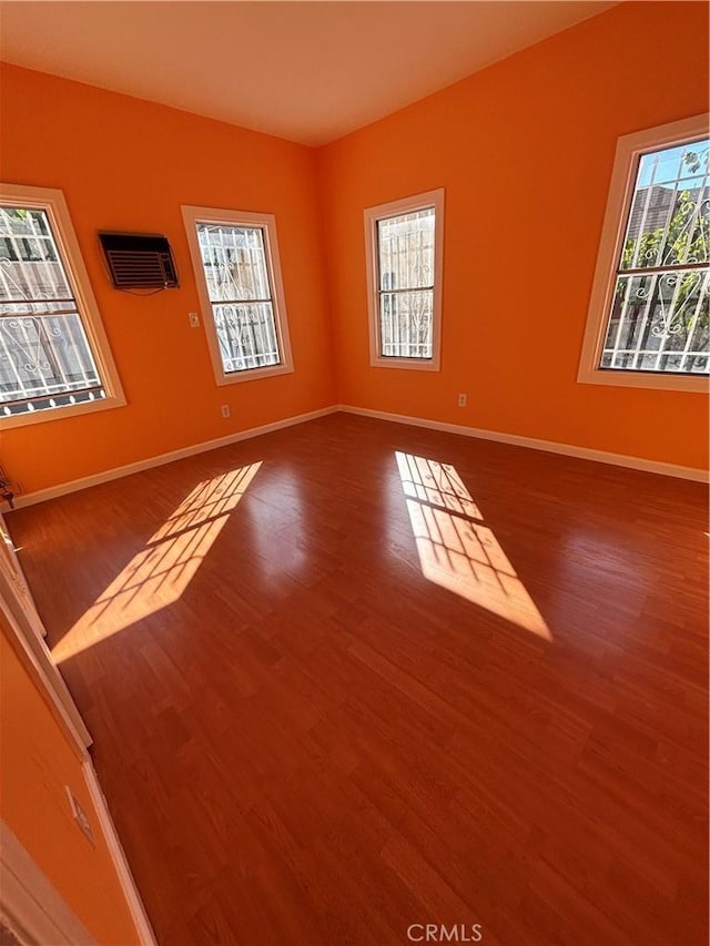 unfurnished room with an AC wall unit and wood-type flooring