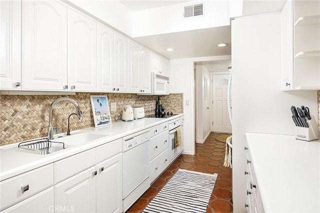 kitchen with white appliances, dark tile patterned flooring, white cabinetry, decorative backsplash, and sink