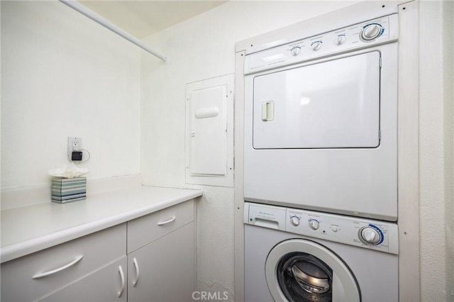 laundry room with stacked washing maching and dryer and cabinets