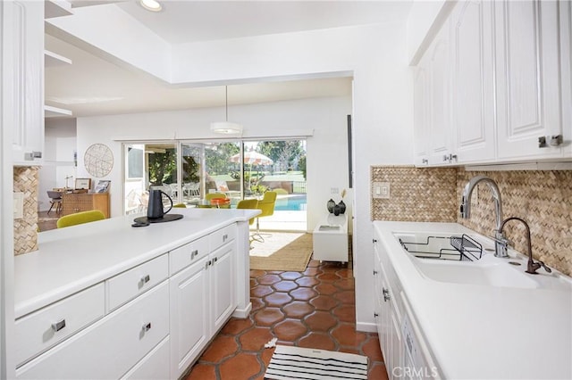 kitchen featuring decorative light fixtures, backsplash, dark tile patterned flooring, sink, and white cabinetry