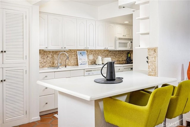 kitchen with tasteful backsplash, white cabinets, and a kitchen breakfast bar