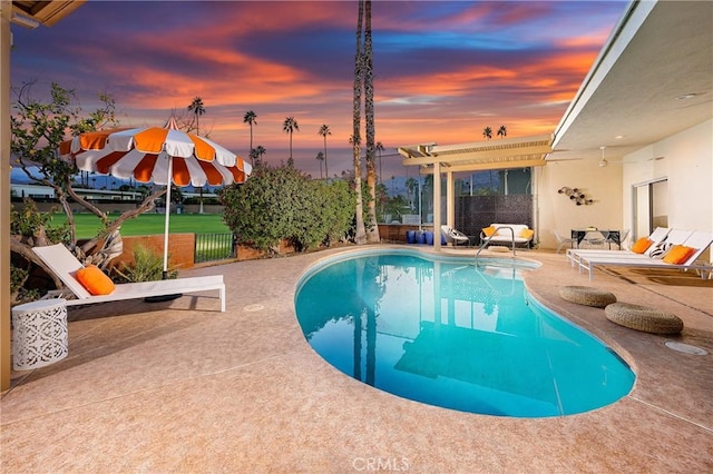 pool at dusk featuring a patio area and a pergola