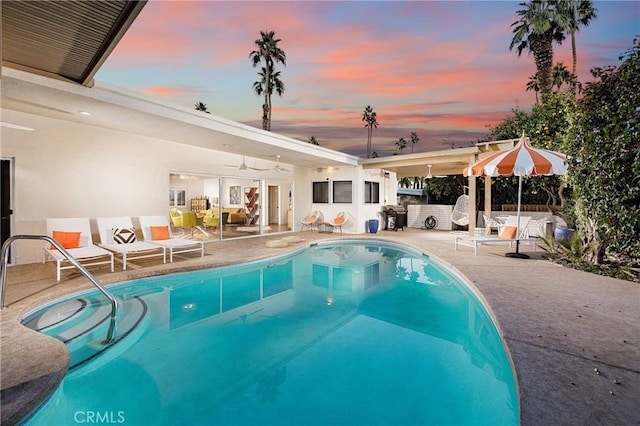 pool at dusk with a patio area