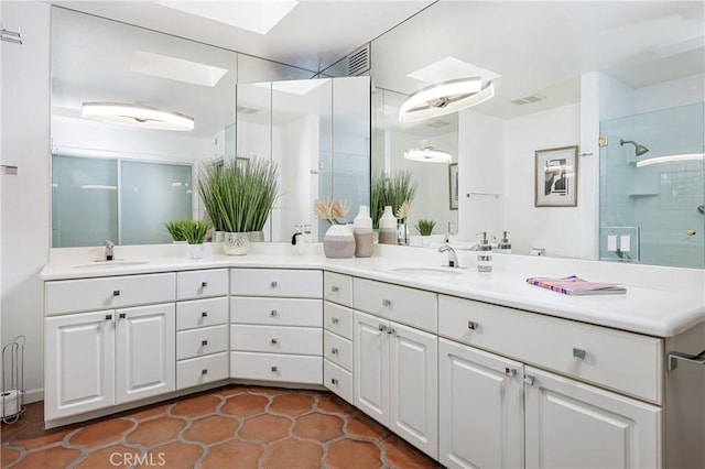 bathroom with a shower with shower door, tile patterned floors, vanity, and a skylight