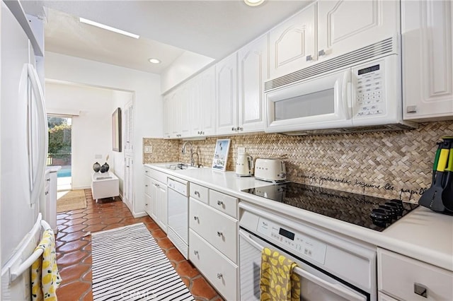 kitchen with tasteful backsplash, sink, white appliances, dark tile patterned floors, and white cabinets