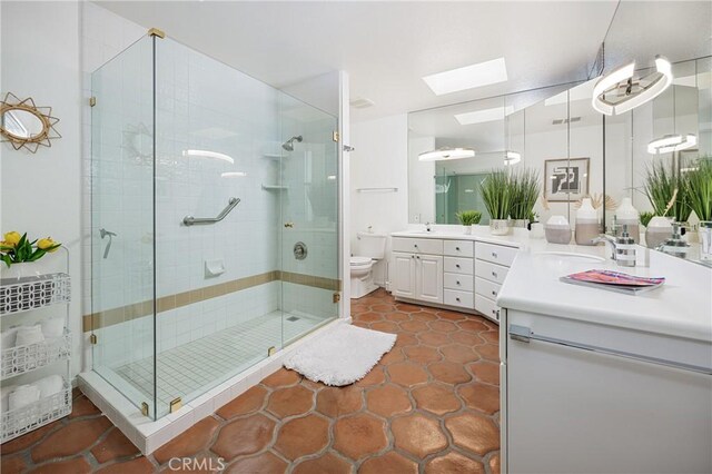 bathroom with toilet, vanity, tile patterned floors, a skylight, and an enclosed shower