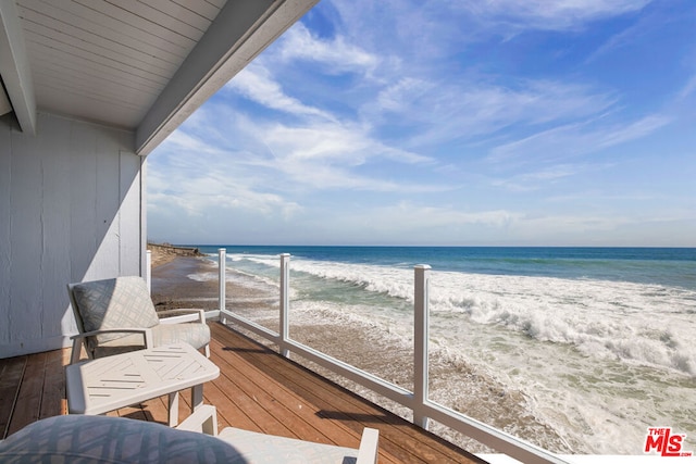 balcony featuring a water view and a beach view