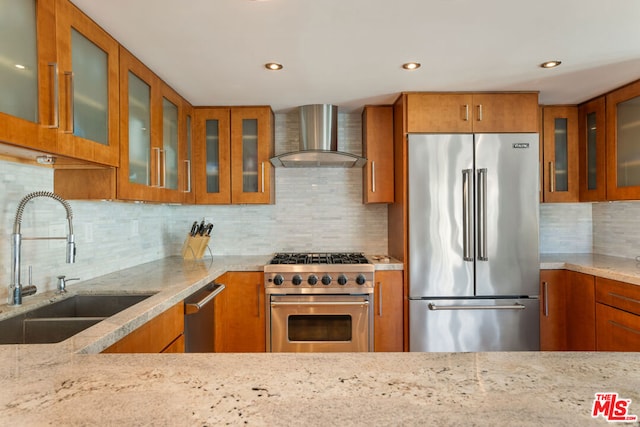 kitchen with sink, wall chimney range hood, backsplash, and high quality appliances