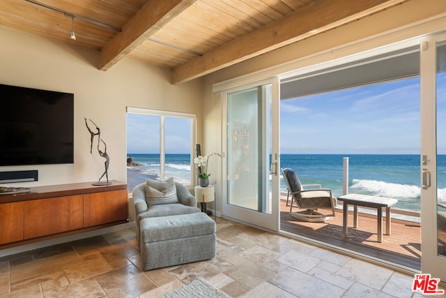 sitting room featuring wooden ceiling, beamed ceiling, a water view, and a view of the beach