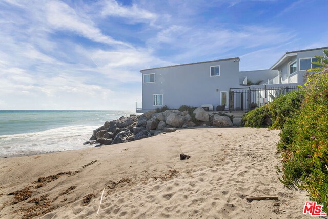 back of property featuring a water view and a view of the beach