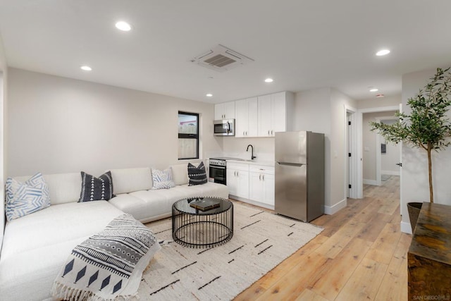 living room with light hardwood / wood-style flooring and sink