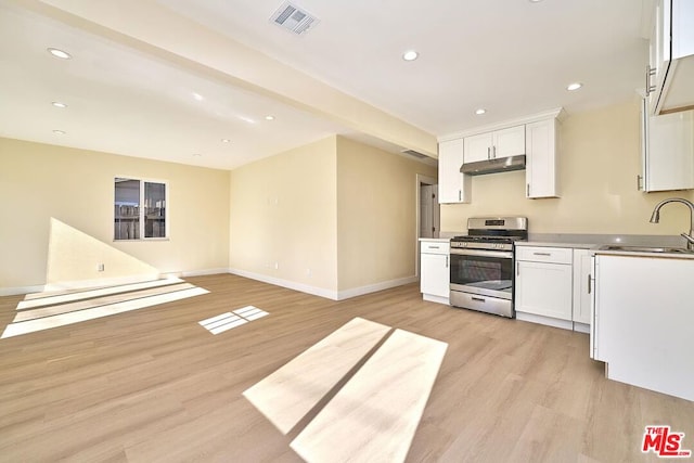 kitchen with light wood-type flooring, white cabinetry, stainless steel range with gas stovetop, and sink