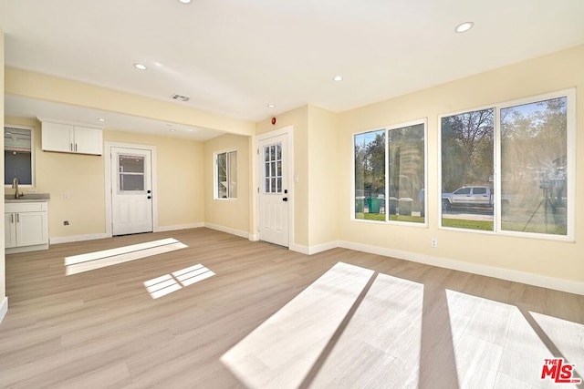 unfurnished living room with sink and light wood-type flooring