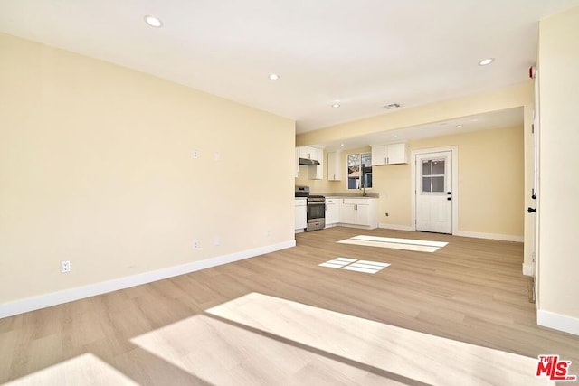 unfurnished living room featuring sink and light hardwood / wood-style flooring