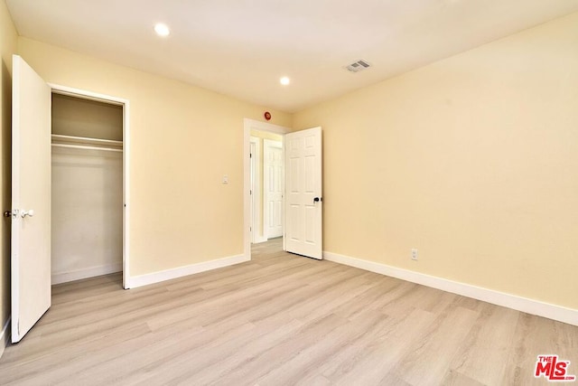 unfurnished bedroom with a closet and light wood-type flooring