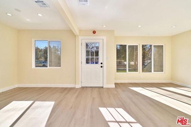 foyer with a wealth of natural light, beam ceiling, and light wood-type flooring