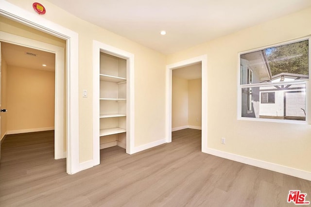 unfurnished bedroom featuring light wood-type flooring, a spacious closet, and a closet