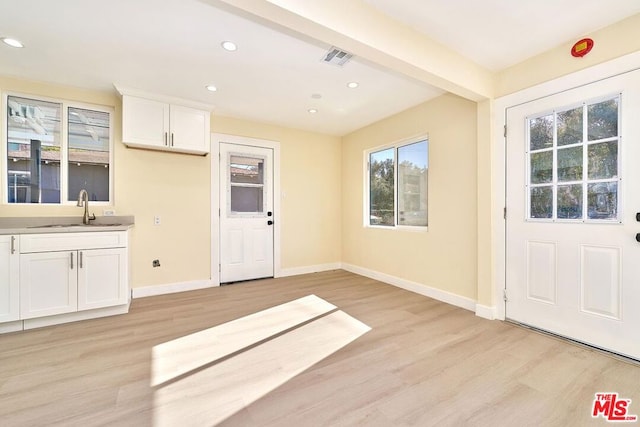 kitchen with sink, white cabinets, and light hardwood / wood-style flooring