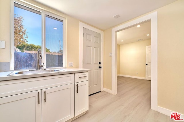 kitchen featuring sink, white cabinets, and light wood-type flooring