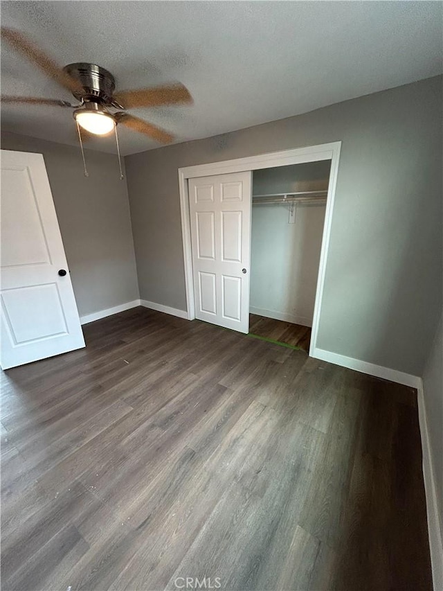 unfurnished bedroom featuring ceiling fan, a textured ceiling, dark hardwood / wood-style floors, and a closet