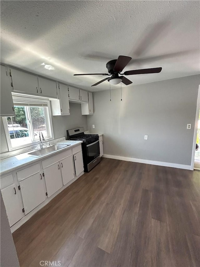 kitchen with a textured ceiling, white cabinets, stainless steel gas range, sink, and dark hardwood / wood-style floors