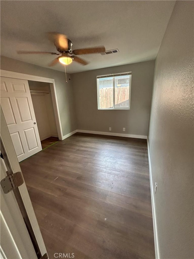 unfurnished bedroom with ceiling fan, a closet, and dark hardwood / wood-style floors