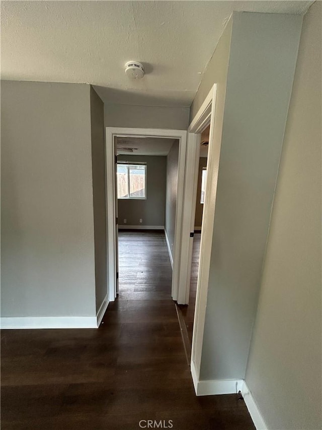 hallway featuring dark wood-type flooring and a textured ceiling